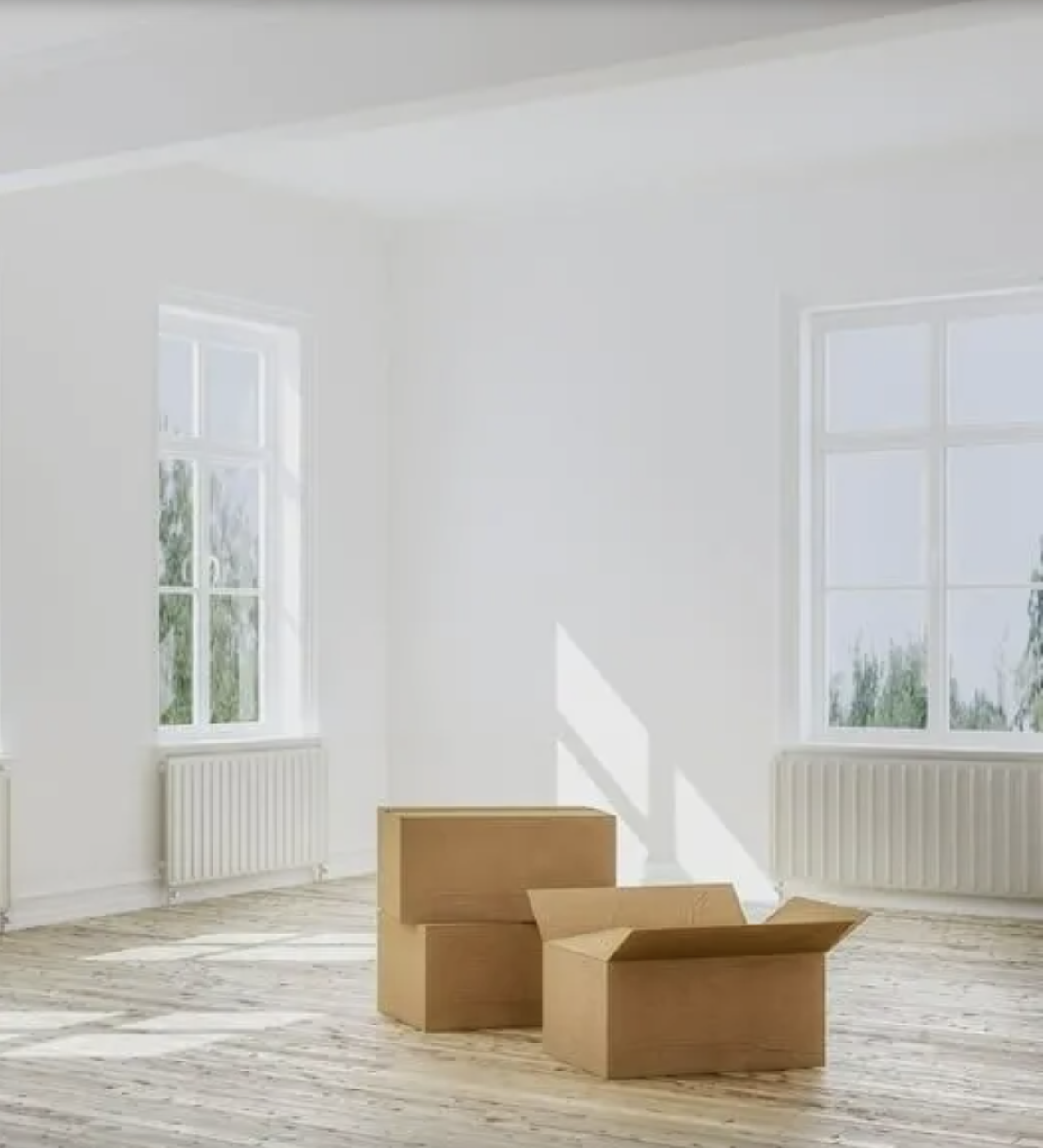 Empty bright room with cardboard moving boxes on wooden floor and two windows